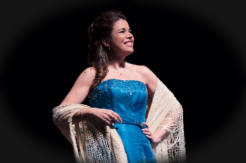 Aida Rioja chantant sur scène avec un châle